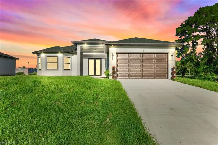 View of front of property featuring an attached garage, concrete driveway, stucco siding, a front yard, and roof with shingles