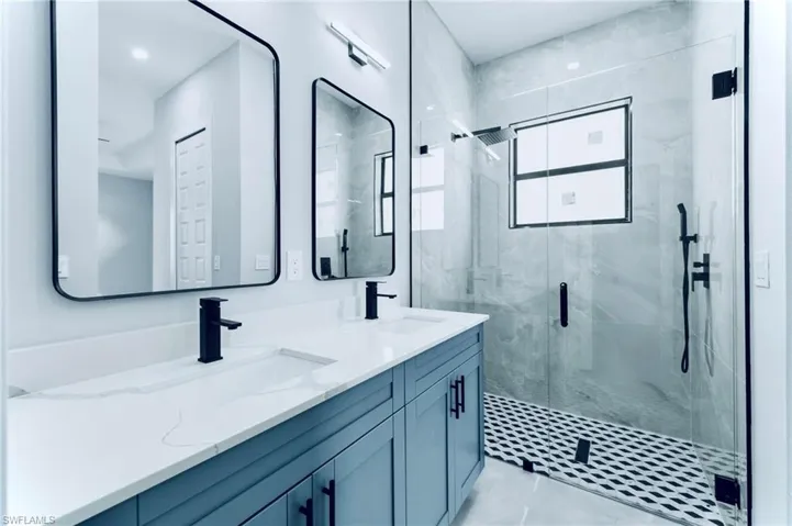 Full bath with a shower stall, double vanity, and light tile patterned floors