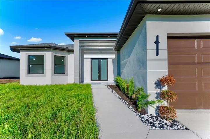 Entrance to property featuring stucco siding, a garage, and french doors