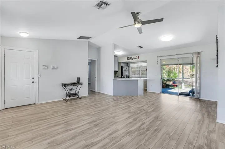 Unfurnished living room with ceiling fan, vaulted ceiling, and light wood finished floors