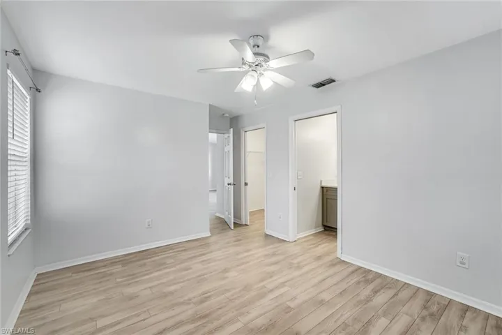 Unfurnished bedroom featuring a walk in closet, light wood finished floors, and ceiling fan