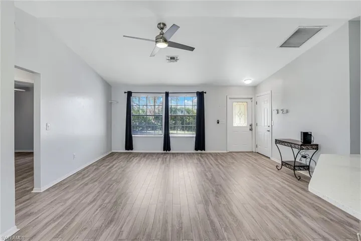 Unfurnished living room featuring light wood-style flooring, vaulted ceiling, and a ceiling fan