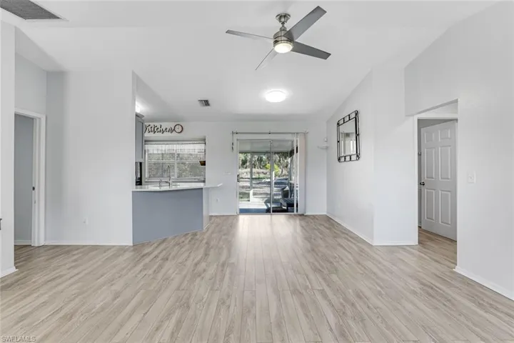 Unfurnished living room with ceiling fan, light wood-style floors, and vaulted ceiling