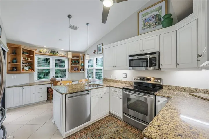 Kitchen featuring white cabinets, appliances with stainless steel finishes, kitchen peninsula, and vaulted ceiling