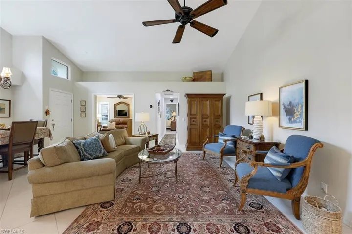 Tiled living room with ceiling fan and high vaulted ceiling