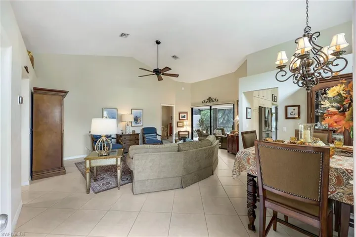 Living room view from front door with ceiling fan with notable chandelier, light tile patterned floors, and high vaulted ceiling