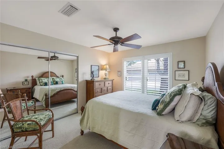 Carpeted bedroom featuring ceiling fan and a closet