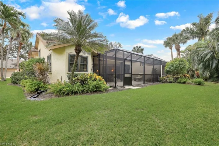 Back of house featuring a lanai and a lawn