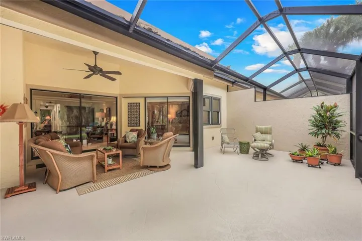 View of patio featuring glass enclosure, an outdoor living space, and ceiling fan