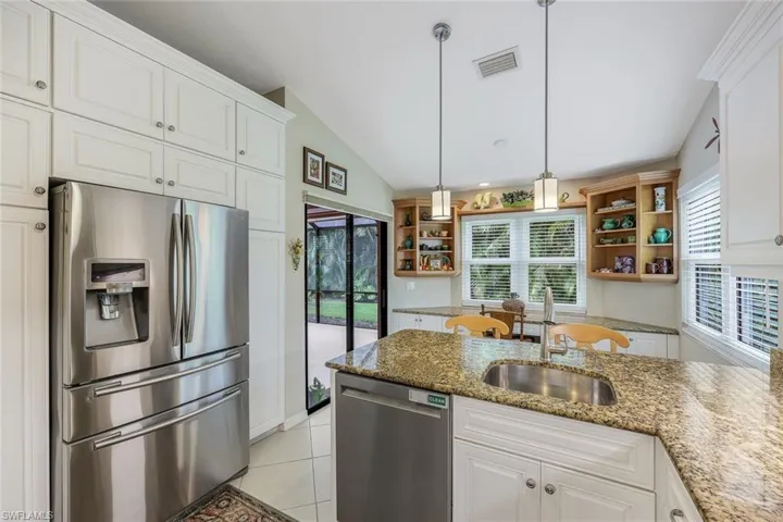 Kitchen featuring sink, dark stone countertops, lofted ceiling, white cabinets, and appliances with stainless steel finishes