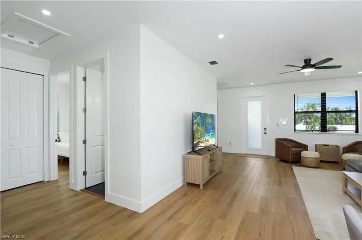 Living room with recessed lighting, light wood-style floors, a ceiling fan, and attic access - Virtually Edited Image