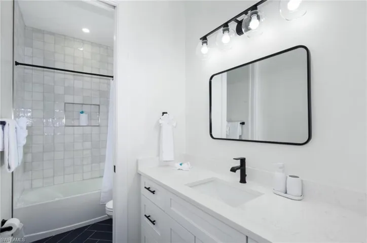 Full bathroom featuring shower / tub combo, vanity, and dark tile patterned floors