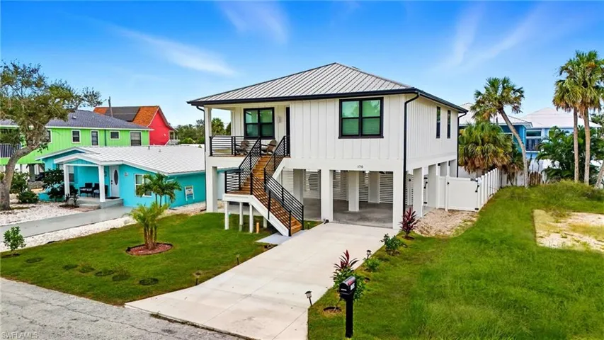 View of front of house featuring a carport, stairway, concrete driveway, board and batten siding, and a metal roof - Virtually Edited Image