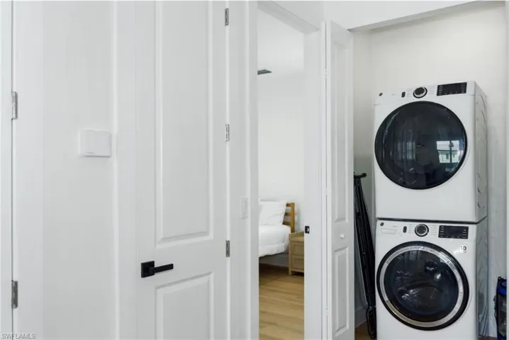 Laundry room with estacked washer and dryer and wood finished floors - Virtually Edited Image
