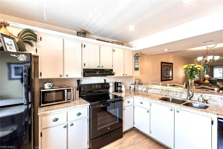 Kitchen with white cabinetry, decorative backsplash, wood style flooring