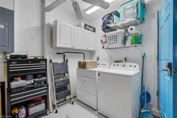 Laundry room featuring electric panel, washing machine and clothes dryer, finished concrete floors, cabinet space, and ceiling fan
