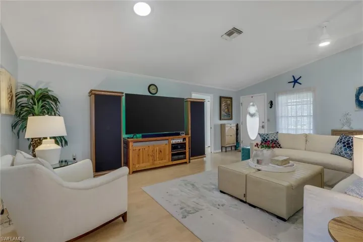 Living area featuring vaulted ceiling, crown molding, and wood finished floors