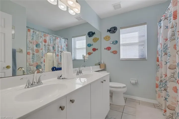 Bathroom with double vanity, light tile patterned floors, and curtained shower