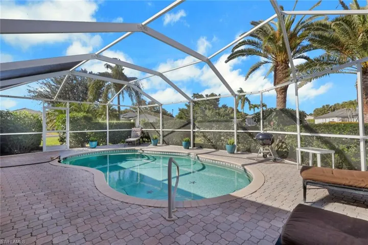Outdoor pool featuring glass enclosure, a patio area, a sunroom, and a grill