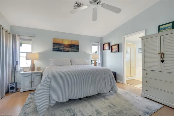 Bedroom featuring vaulted ceiling, light wood finished floors, a ceiling fan, and connected bathroom