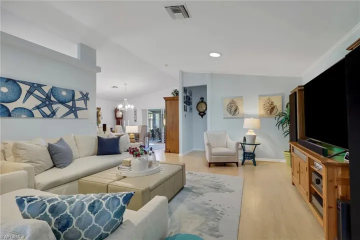 Living room featuring light wood-style flooring, a chandelier, and lofted ceiling