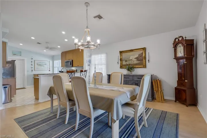 Dining area with a chandelier, light wood-type flooring, vaulted ceiling, and ceiling fan