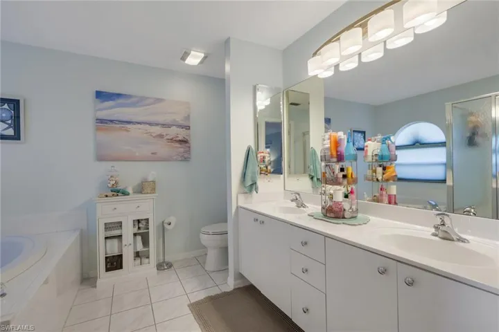 Bathroom featuring a bath, double vanity, light tile patterned flooring, and a shower with shower door
