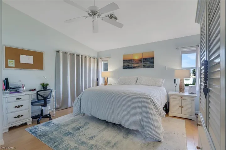 Bedroom with light wood-style floors, a ceiling fan, and lofted ceiling
