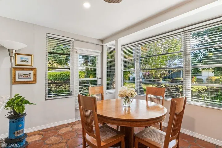 Light and bright sun/family/dining room with a large bank of windows for natural light, tiled patterned floors, and an exterior door out to the relaxing patio area on the rear of the home.