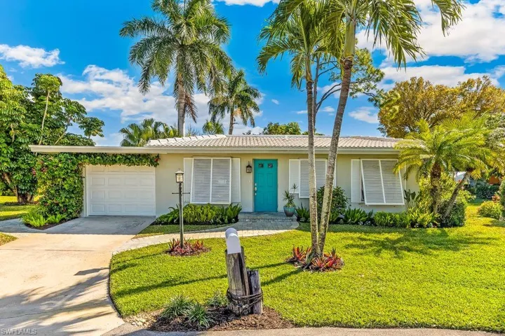 Single story home with concrete driveway, tiled roof, beautifully landscaped yard with mature plantings, Bahama style window coverings, and a one car attached garage.