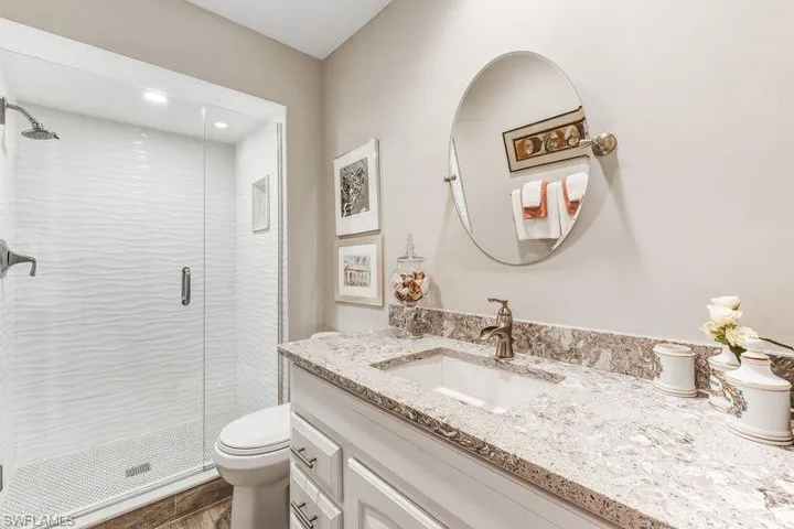 Updated Primary/Master Bathroom with newer vanity, beautiful walk-in oversized shower, tiled wood-look flooring, and recessed lighting.