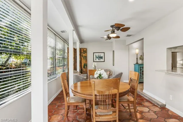 Light and bright sun/family/dining room with a large bank of windows for natural light, tiled patterned floors, and an exterior door out to the relaxing patio area on the rear of the home.
