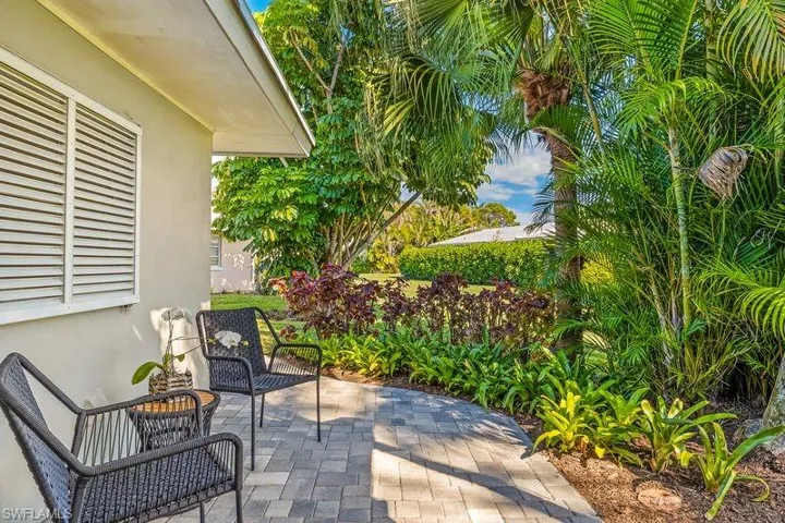 Beautiful patio/sitting area with lush landscaping on the rear of the home with access to the sun/family room and new pavers with a walkway to the exterior garage side-door and front of the home.
