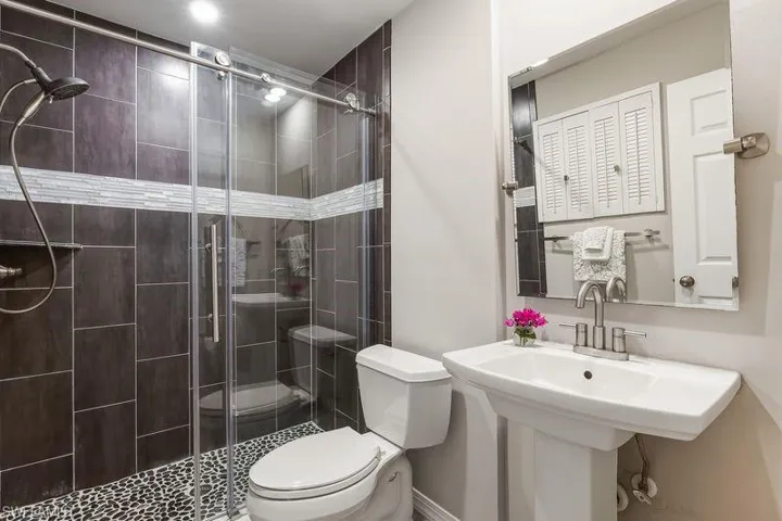 Updated Guest/2nd Bathroom with newer pedestal sink, beautiful walk-in oversized shower, tiled wood-look flooring, and recessed lighting.