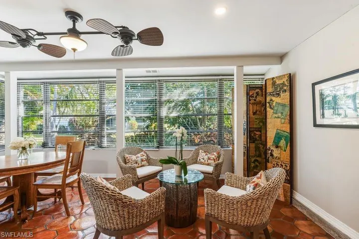 Light and bright sun/family/dining room with a large bank of windows for natural light, tiled patterned floors, and an exterior door out to the relaxing patio area on the rear of the home.
