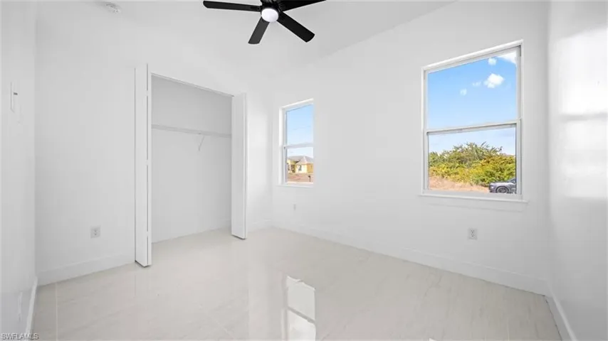 Unfurnished bedroom with ceiling fan and a closet