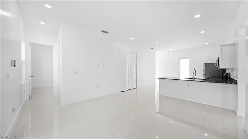 Kitchen featuring recessed lighting, white cabinets, a peninsula, open floor plan, and dark stone counters