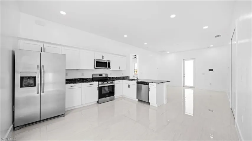 Kitchen with appliances with stainless steel finishes, white cabinets, recessed lighting, a peninsula, and open floor plan