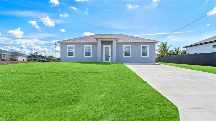 View of front facade with driveway, stucco siding, and roof with shingles
