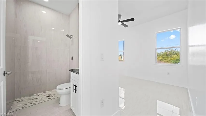 Bathroom with a tile shower, vanity, and a ceiling fan