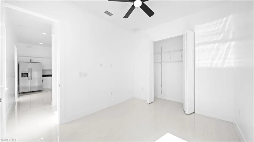 Unfurnished bedroom featuring stainless steel fridge, a closet, and ceiling fan