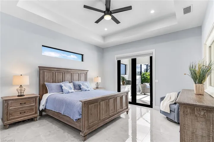 Bedroom featuring a tray ceiling, ceiling fan, access to outside, light marble finish floors, and recessed lighting