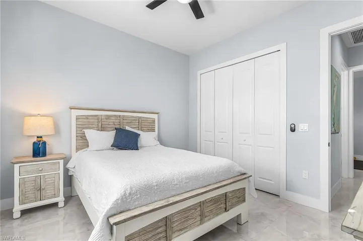 Bedroom with light marble finish floors, a closet, and a ceiling fan