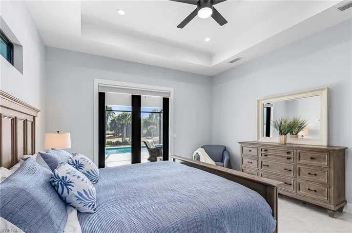 Bedroom with access to exterior, a tray ceiling, a ceiling fan, and recessed lighting