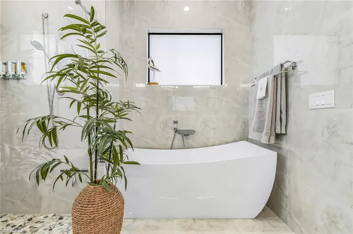 Full bathroom with a soaking tub and tile walls