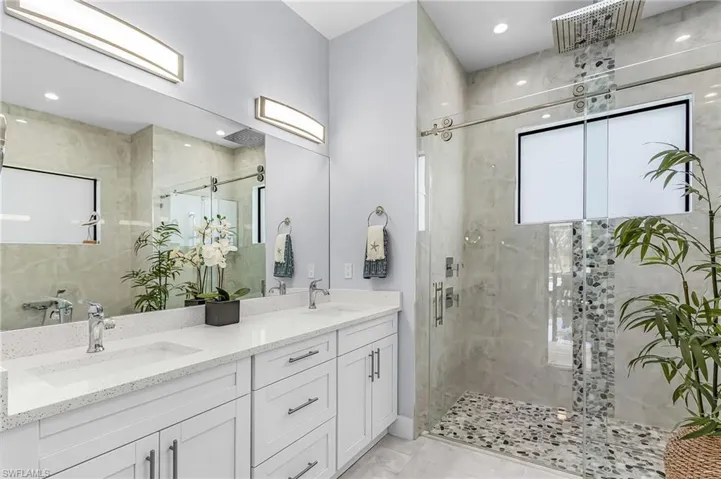 Bathroom with a stall shower, double vanity, and recessed lighting