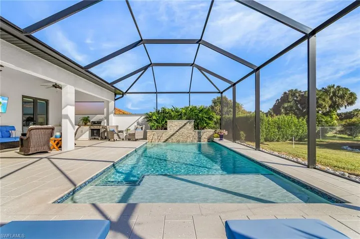 Outdoor pool featuring a sunroom, glass enclosure, a patio, and exterior kitchen