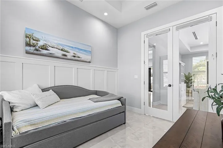 Bedroom featuring french doors, a decorative wall, light marble finish floors, recessed lighting, and wainscoting