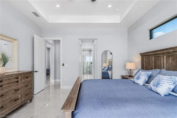 Bedroom featuring light marble finish floors, a raised ceiling, a ceiling fan, and recessed lighting