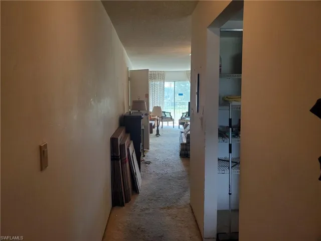 Hall featuring a textured ceiling and light carpet